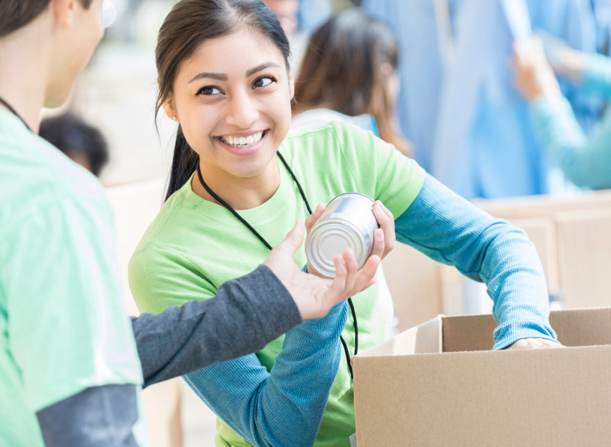 volunteer handing canned food to woman smiling