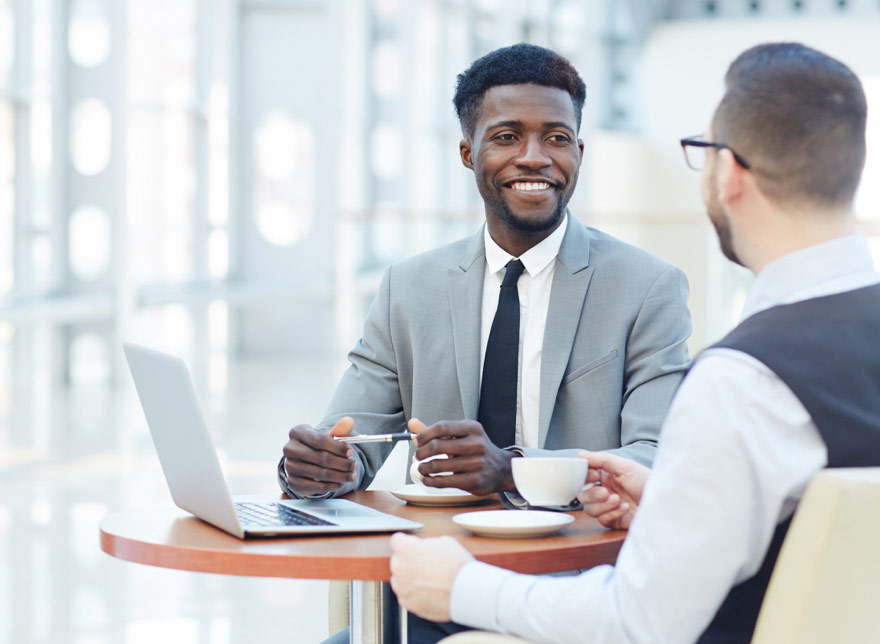 Two businessmen sitting at a table conversing.